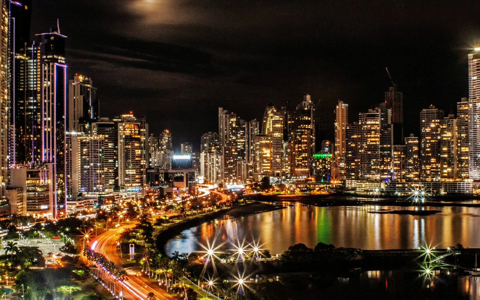 Die beleuchtete Skyline von Panama City bei Nacht, gespiegelt in der Bucht.
