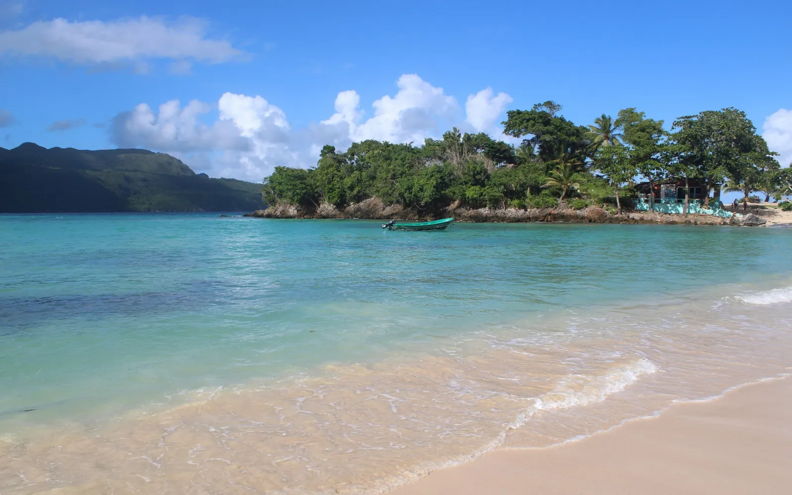 Türkises Wasser und eine bewaldete Insel vor grünen Hügeln an der Küste von Samaná.
